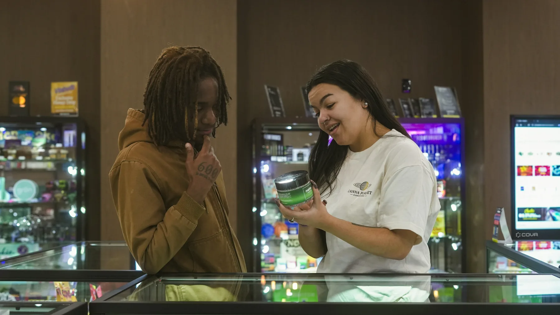 Two adult customers smiling together while comparing a product at a dispensary counter