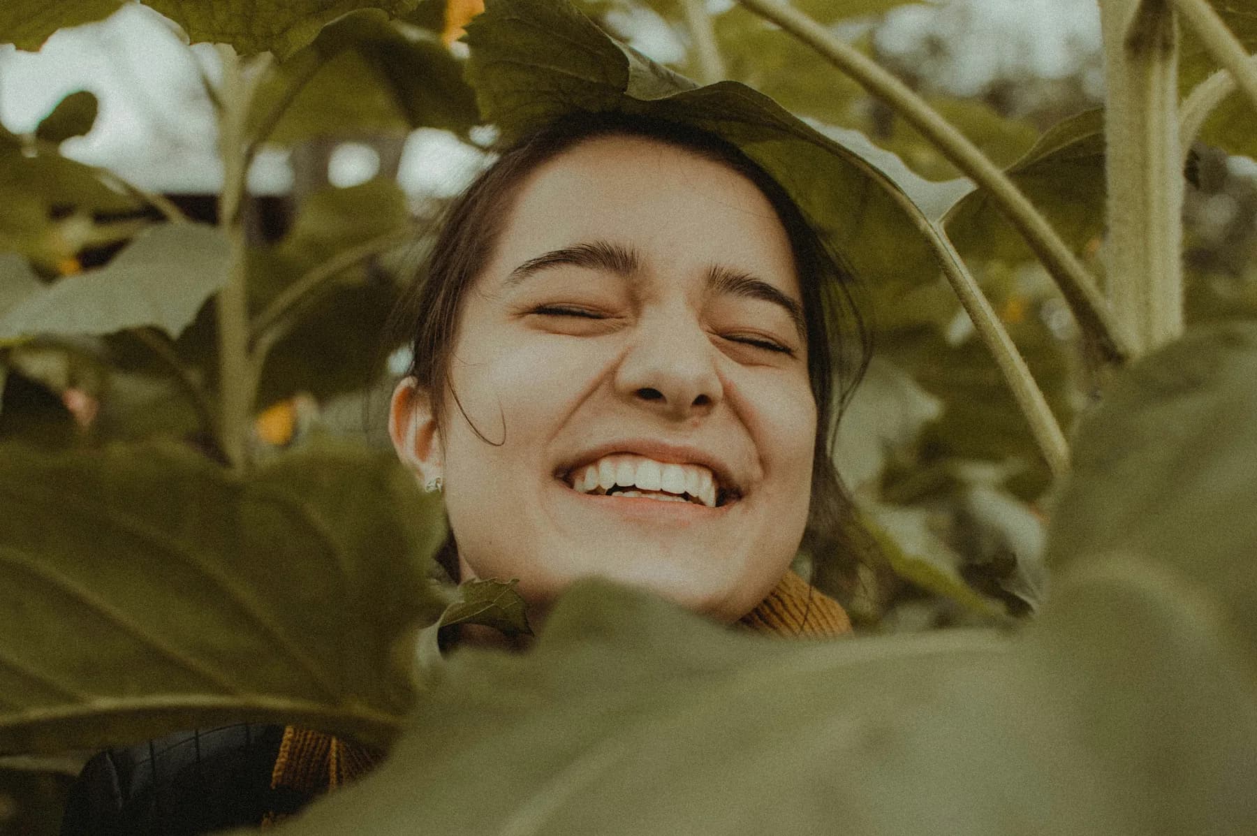Adult customer smiling outdoors among green foliage