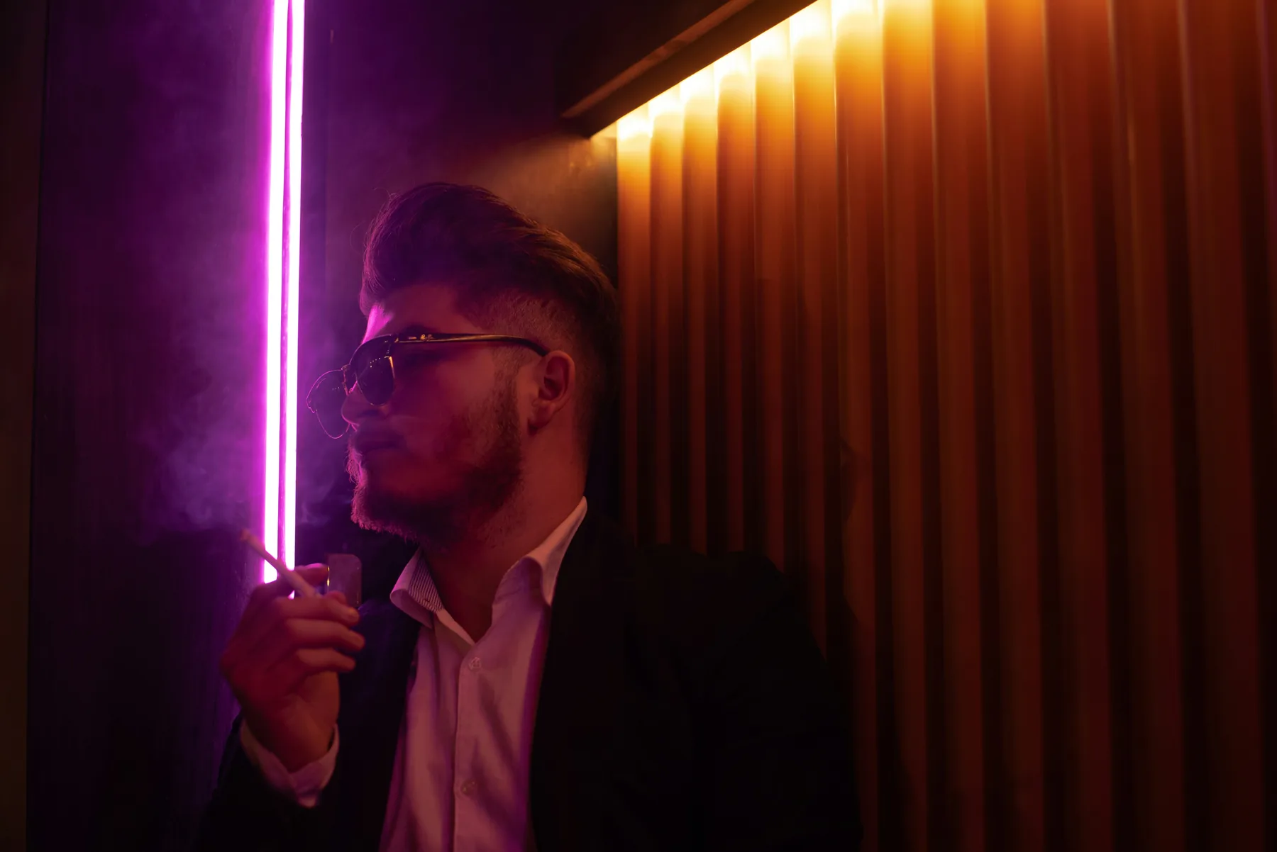 Adult in a dark interior lit by a vertical magenta light