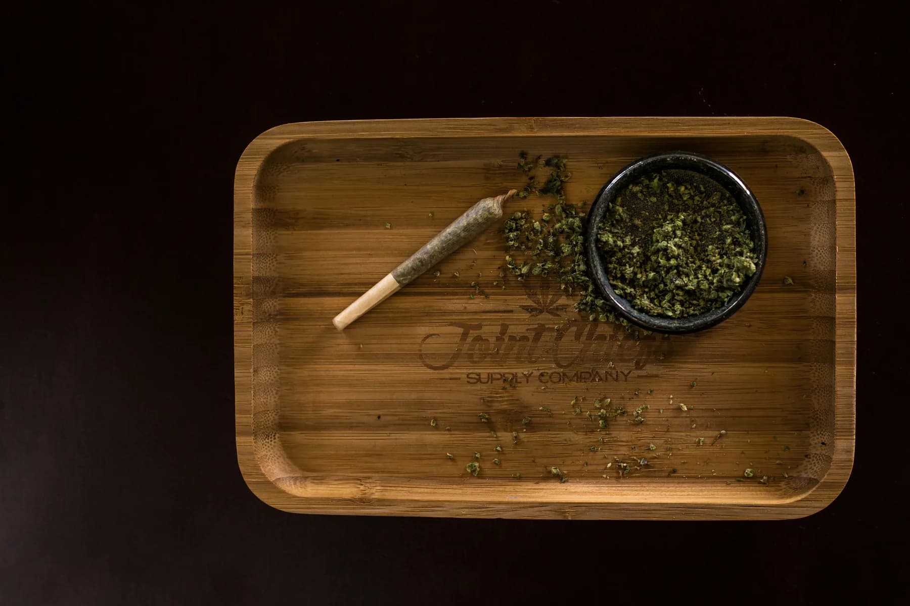 Prepared cannabis roll and flower arranged on a wooden tray