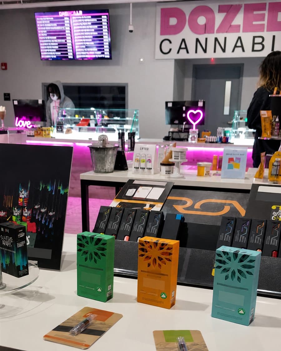 Dazed Cannabis counter display with packaged products arranged under pink accent lighting