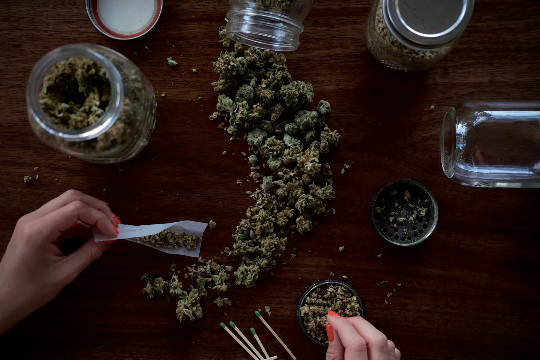 Overhead view of adult hands preparing cannabis on a wooden table